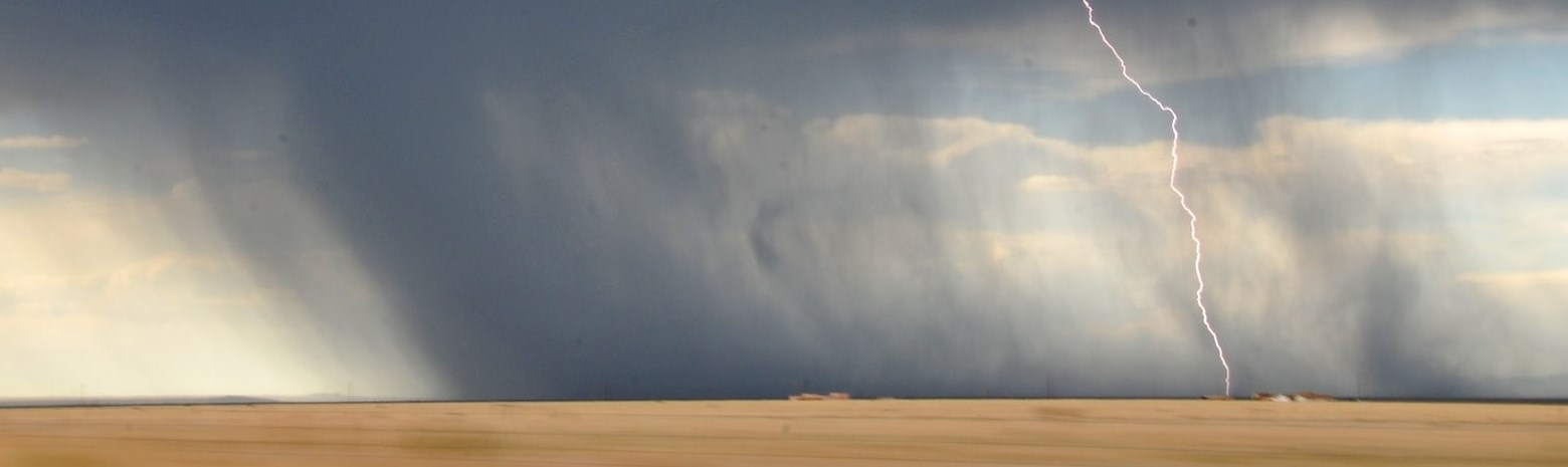 Dark funnel cloud with lightening strike in wheat field