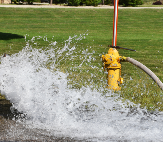 A picture of a yellow fire hydrant being flushed out.