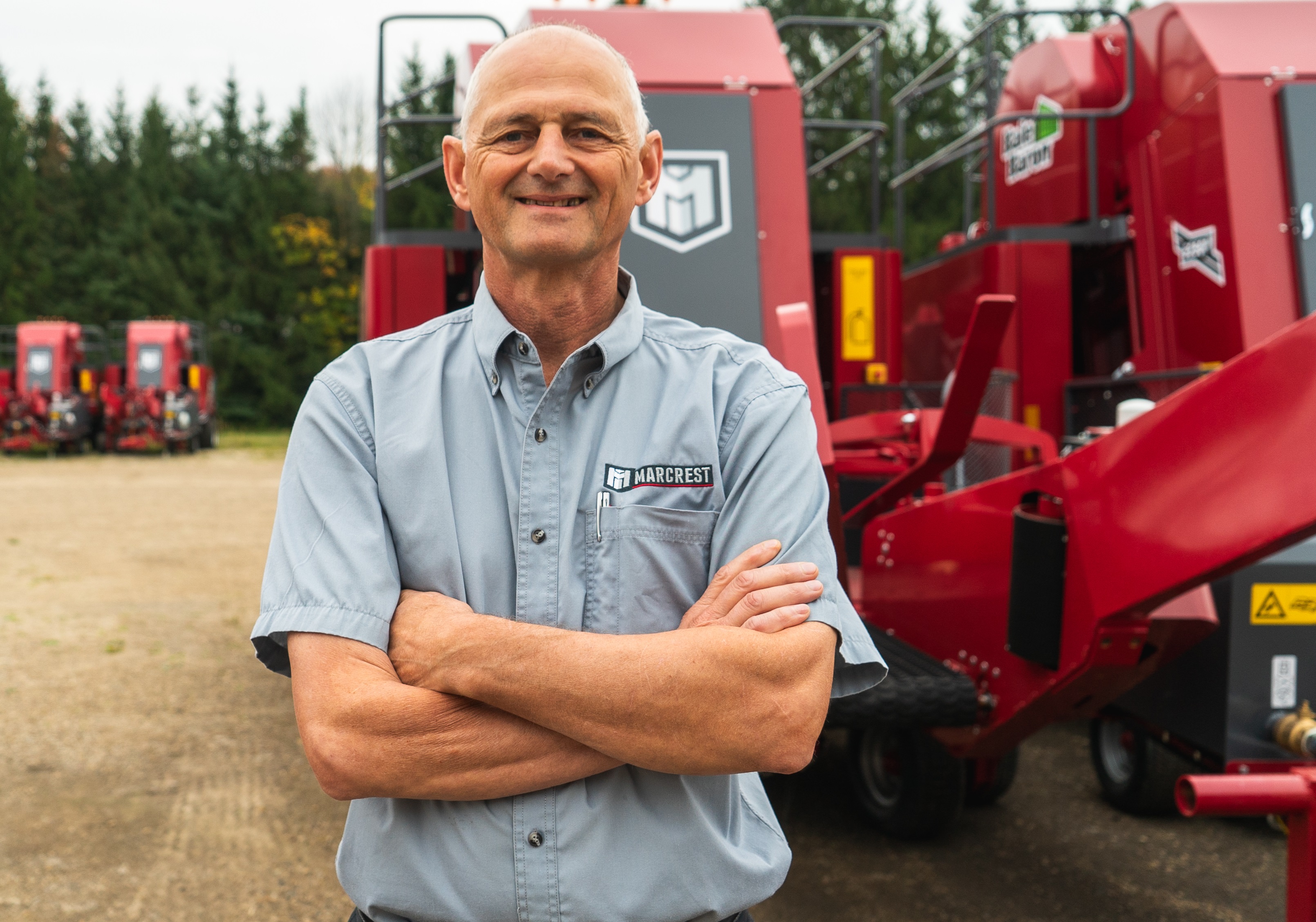 A picture of the owner of Marcrest standing in front of their Bale Baron.