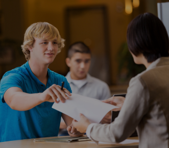 A picture of a young man in a blue shirt handing over a resume.