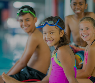 A picture of kids sitting on the edge of a pool.